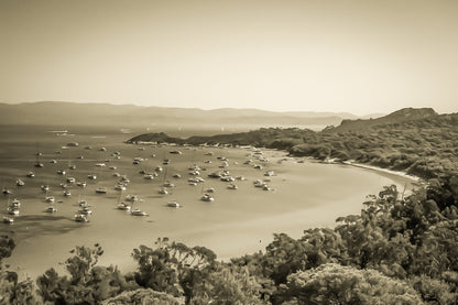 Vue plongeante sur la grande baie de Porquerolles avec de nombreux bateaux ancrés dans une eau turquoise sous un ciel d’été, vintage