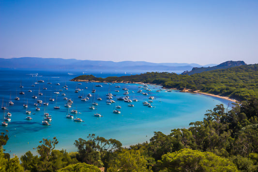 Vue plongeante sur la grande baie de Porquerolles avec de nombreux bateaux ancrés dans une eau turquoise sous un ciel d’été