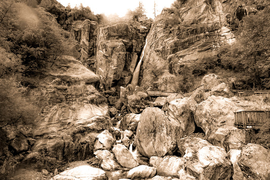 Panorama de la cascade du Ray entourée de falaises et de blocs rocheux, ambiance montagneuse en ton sépia