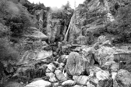 Panorama de la cascade du Ray entourée de falaises et de blocs rocheux, ambiance montagneuse, noir et blanc