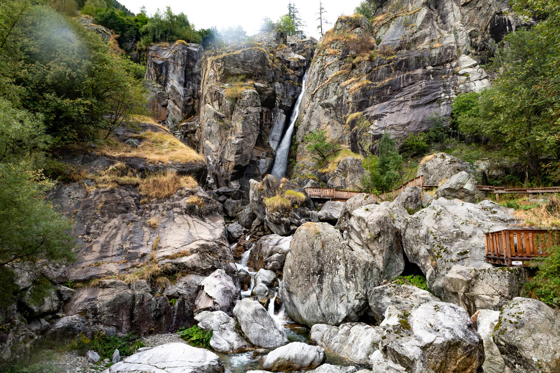 Panorama de la cascade du Ray entourée de falaises et de blocs rocheux, ambiance montagneuse, couleur