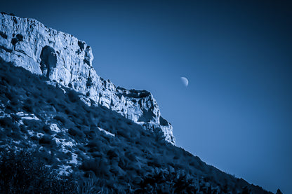 Falaise de la Sainte-Baume et lune baignant dans une dominante bleutée, atmosphère nocturne et mystérieuse.