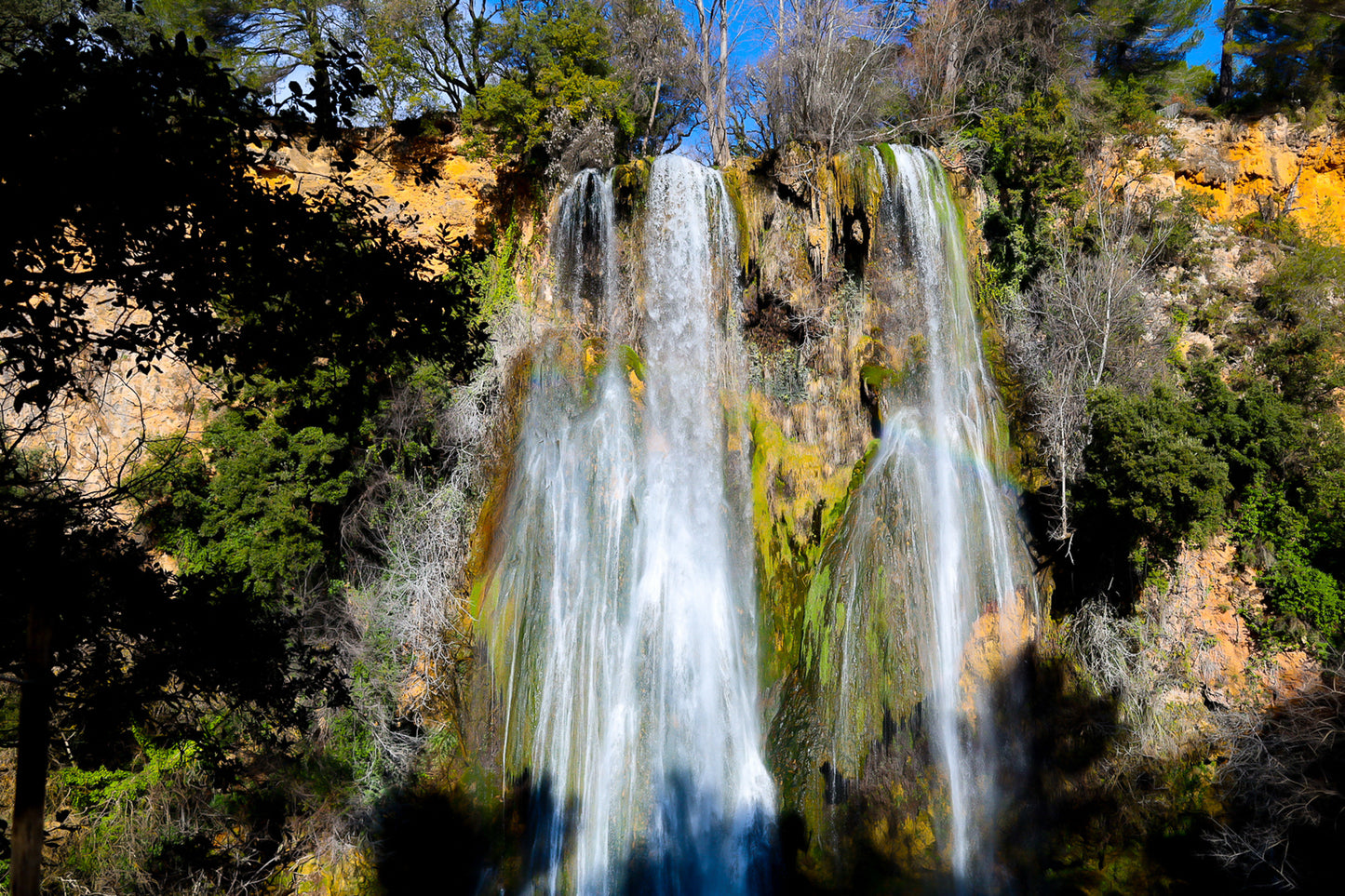 Grande cascade de Sillans tombant en rideaux blancs sur une paroi ocre et moussue, encadrée par la végétation