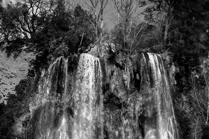 Deux pans de cascade à Sillans dévalant la falaise, entourés d’arbres nus et de mousse verte, version noir et blanc