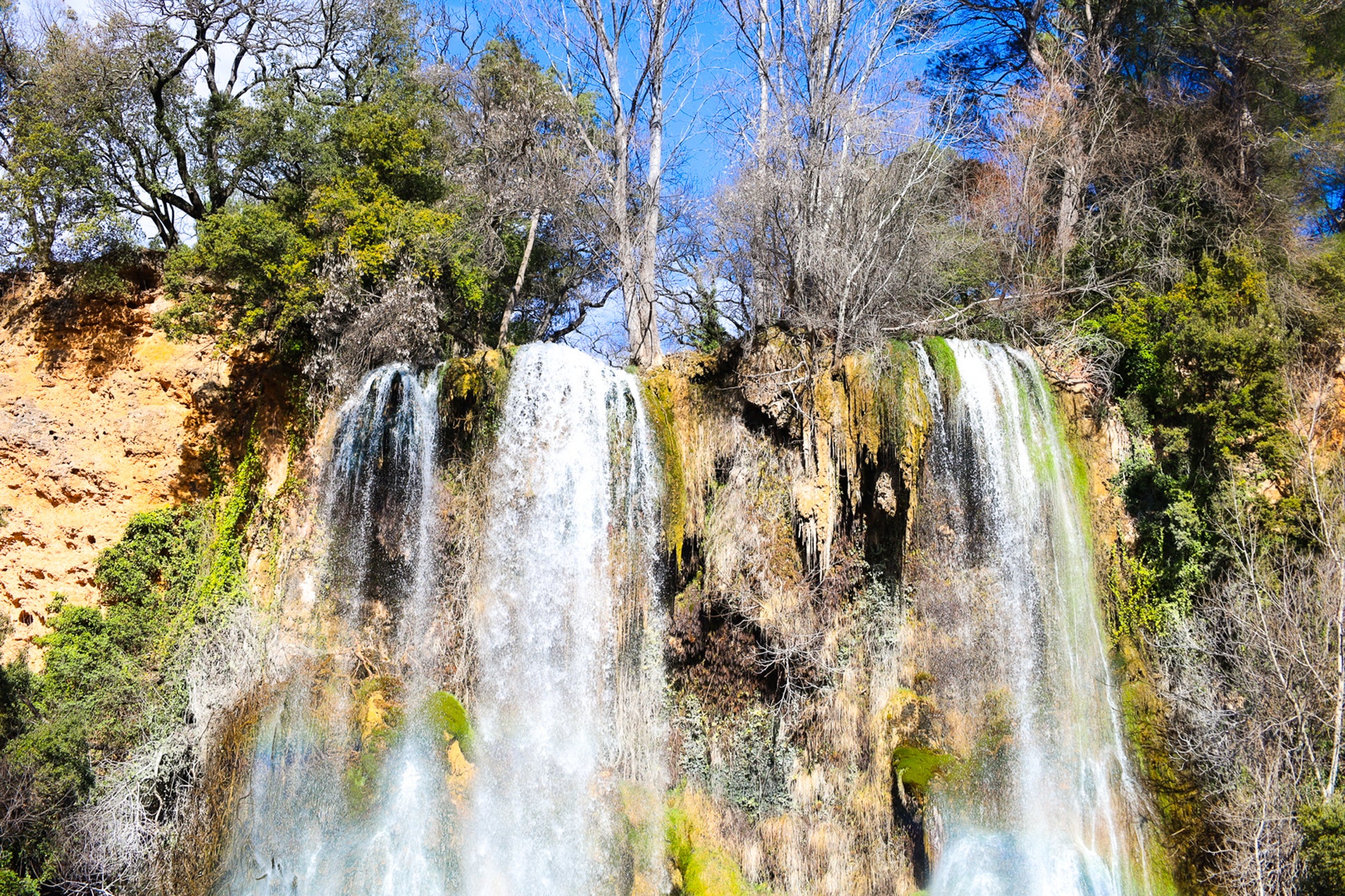 Deux pans de cascade à Sillans dévalant la falaise, entourés d’arbres nus et de mousse verte