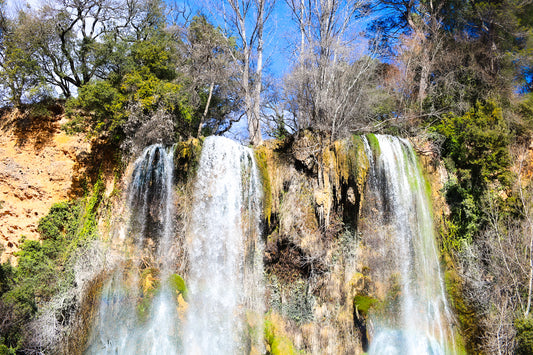 Deux pans de cascade à Sillans dévalant la falaise, entourés d’arbres nus et de mousse verte
