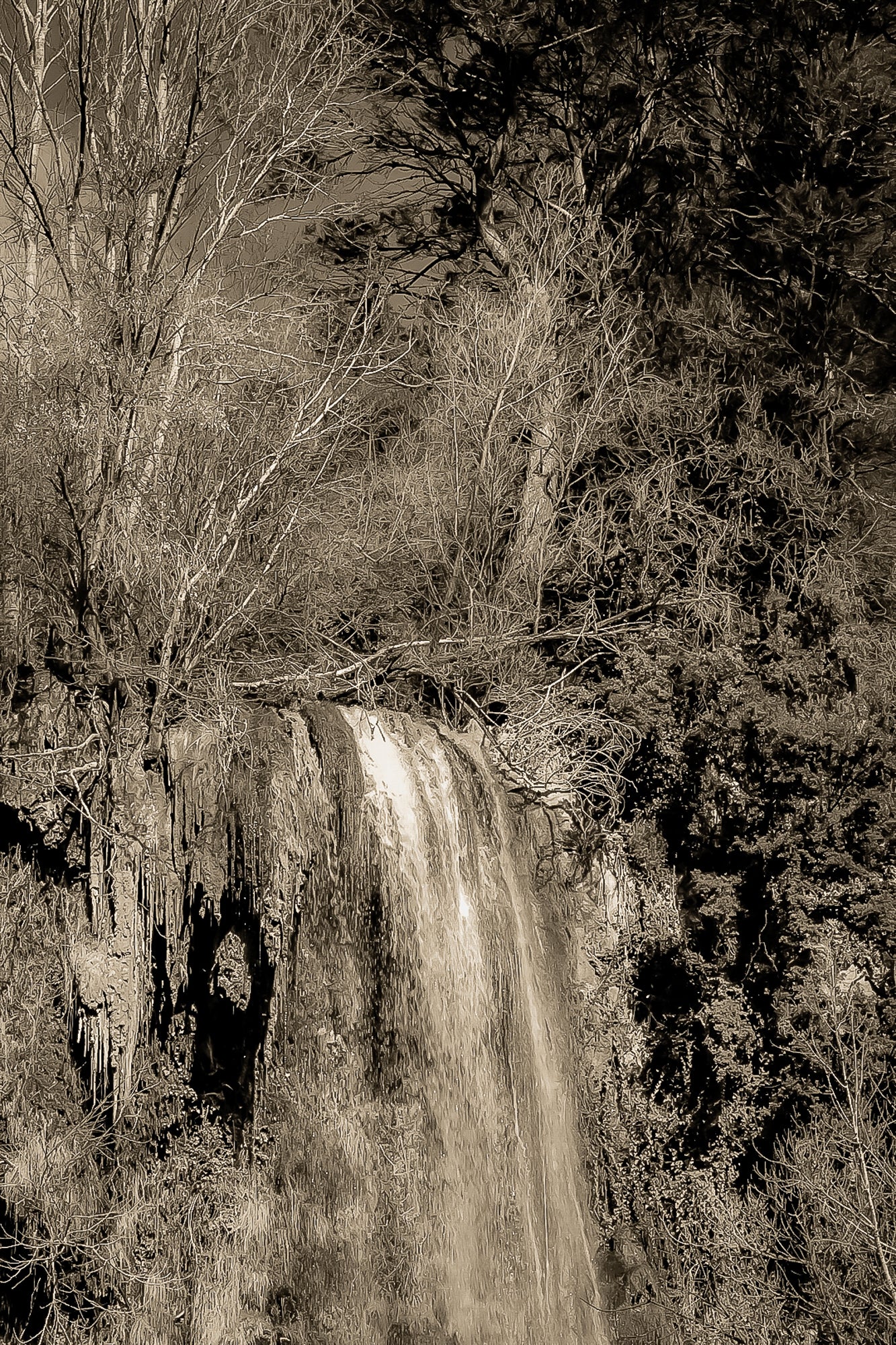 Gros plan vertical sur la cascade de Sillans avec eau ruisselante et mousses vertes accrochées à la falaise, vintage