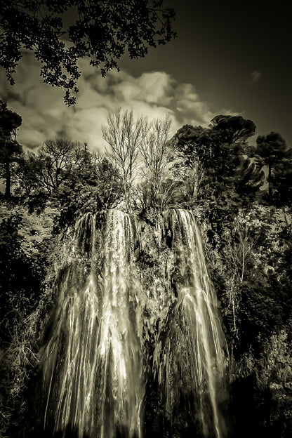 Haute cascade de Sillans se détachant sur un ciel bleu, encadrée par les arbres de la forêt, vintage