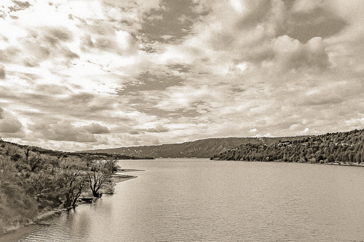 Large vue sur le lac de Sainte-Croix depuis un pont, rives boisées et grand ciel nuageux, vintage