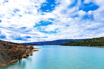 Large vue sur le lac de Sainte-Croix depuis un pont, rives boisées et grand ciel nuageux