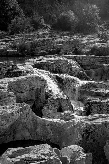 Bloc de calcaire creusé et cascade encaissée à la cascade du Sautadet, paysage minéral dominé par les rochers, noir et blanc