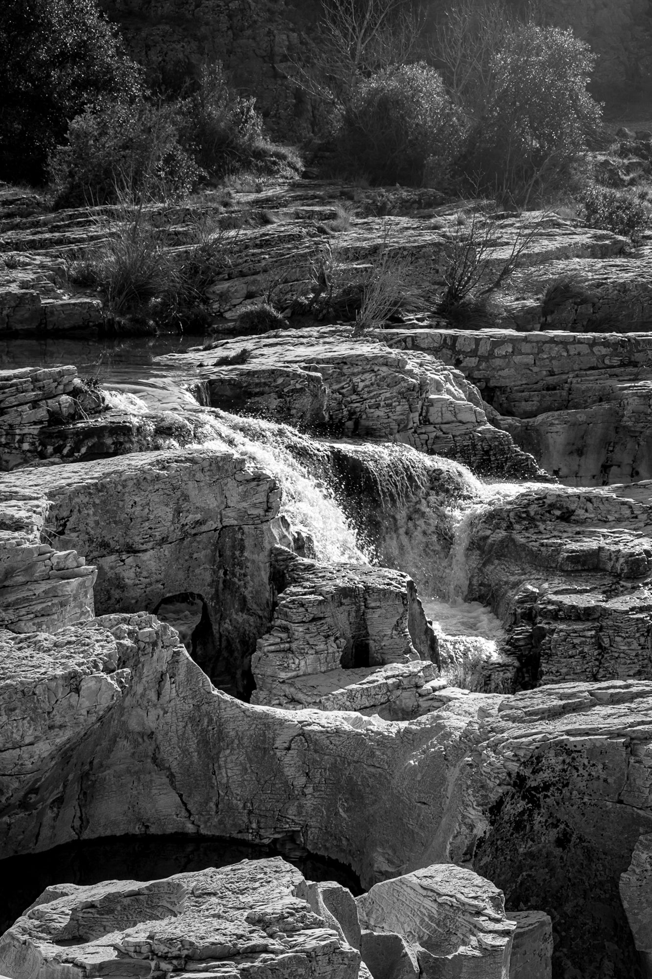Bloc de calcaire creusé et cascade encaissée à la cascade du Sautadet, paysage minéral dominé par les rochers, noir et blanc
