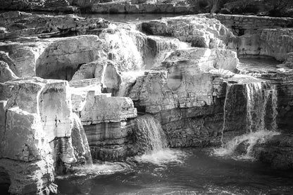 Ensemble de chutes superposées tombant dans un bassin turquoise à la cascade du Sautadet, noir et blanc