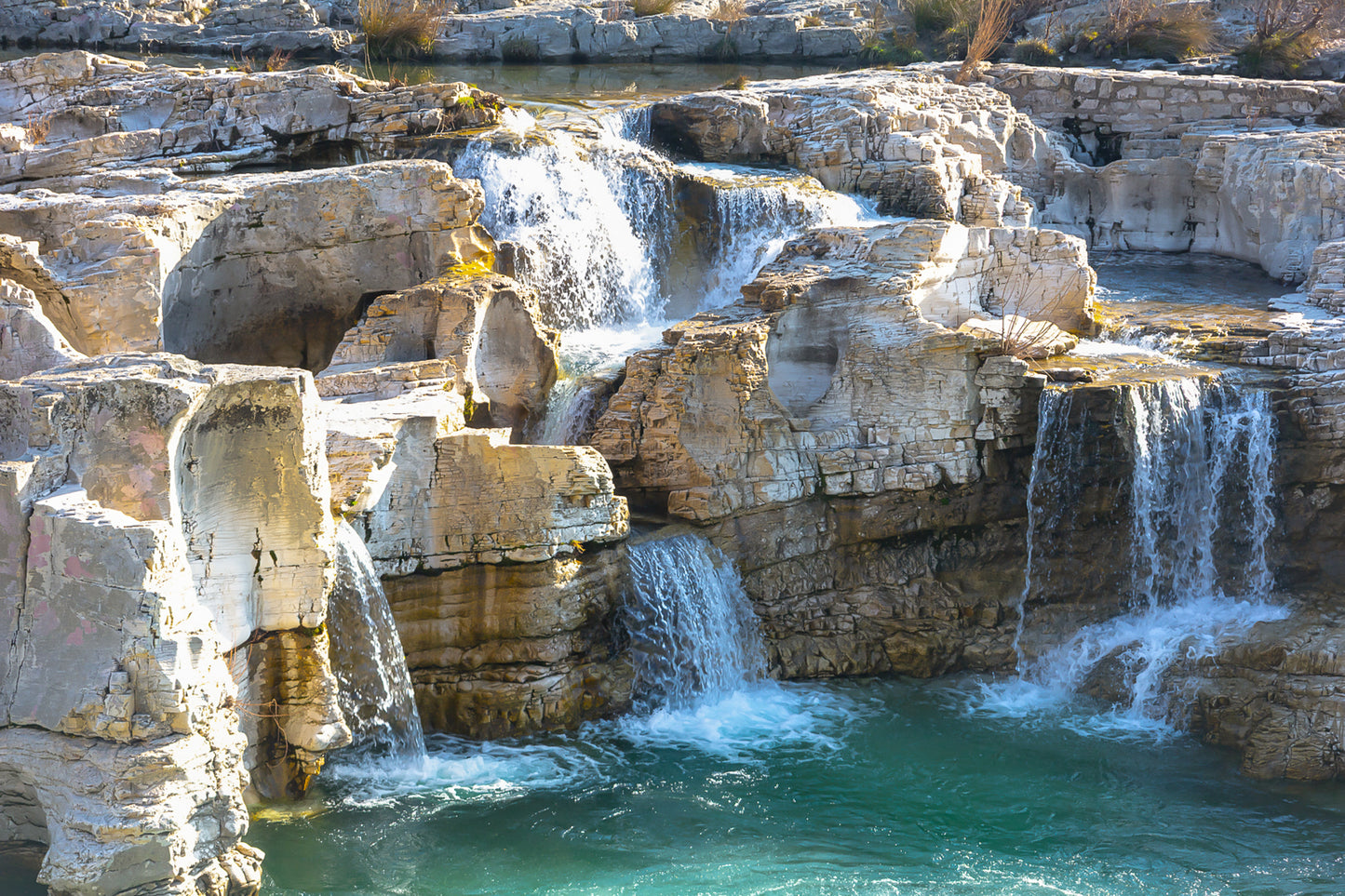 Ensemble de chutes superposées tombant dans un bassin turquoise à la cascade du Sautadet