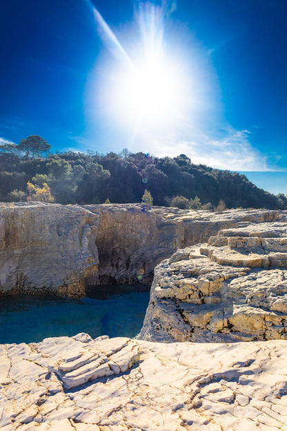 Soleil au zénith au-dessus des falaises claires et de l’eau bleu profond à la cascade du Sautadet.