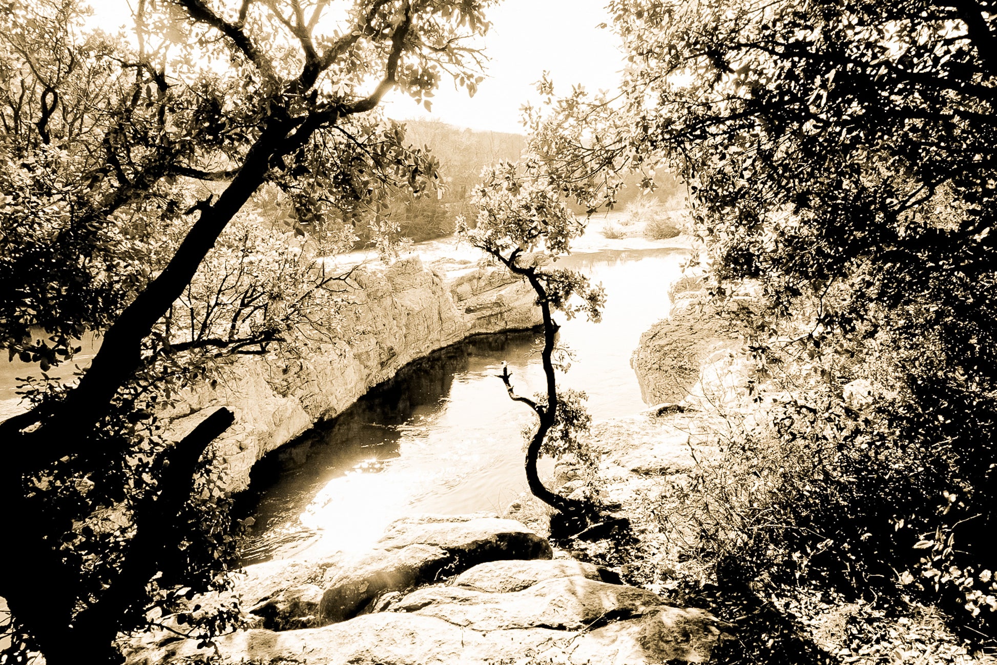 Courbe de la rivière Cèze vue à travers un encadrement d’arbres et de rochers à la cascade du Sautadet, vintage