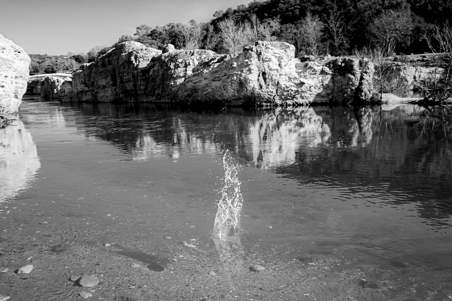 Goutte d’eau éclatant en gerbe au centre de la rivière turquoise à la cascade du Sautadet, falaises claires en reflet, noir et blanc