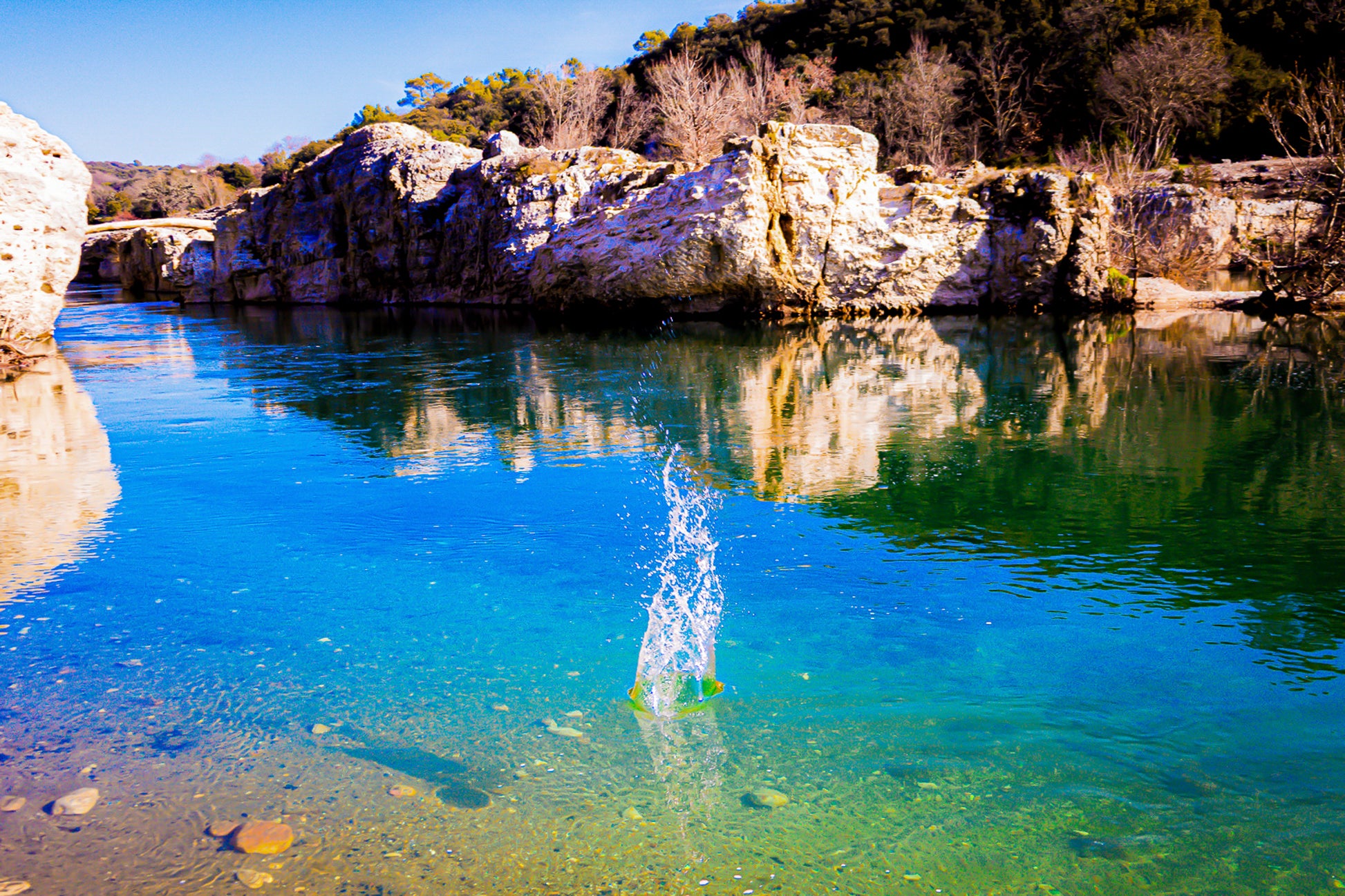 Goutte d’eau éclatant en gerbe au centre de la rivière turquoise à la cascade du Sautadet, falaises claires en reflet