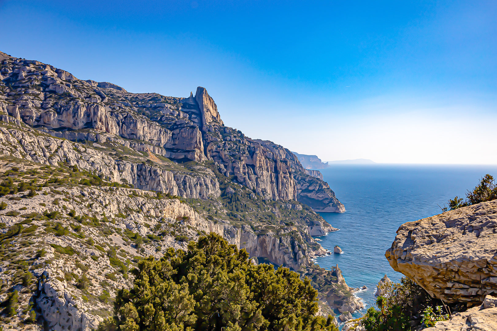 Falaises monumentales des calanques de Sugiton plongeant vers la Méditerranée par ciel bleu profond