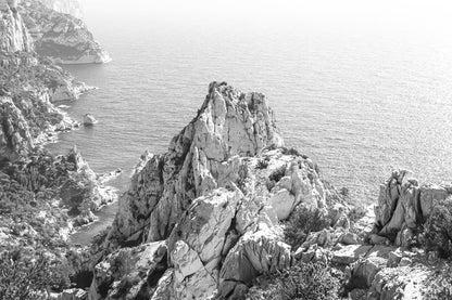 Pic calcaire élancé face à la mer, relief emblématique des calanques de Sugiton, noir et blanc