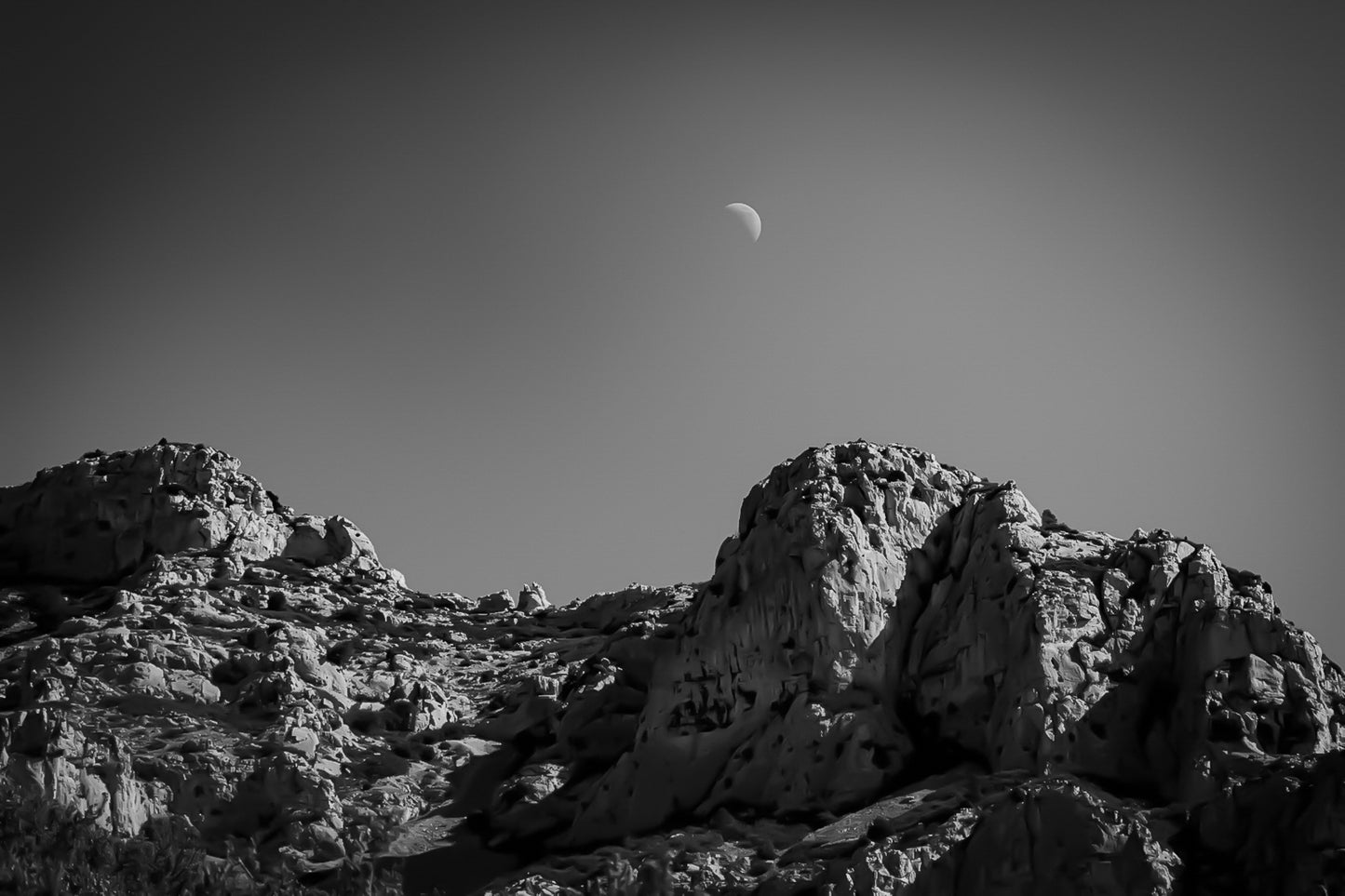 Demi-lune au-dessus des crêtes calcaires de Sugiton, ciel bleu profond et relief minéral, noir et blanc