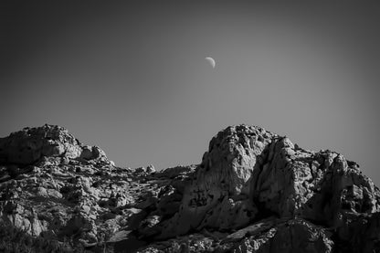 Demi-lune au-dessus des crêtes calcaires de Sugiton, ciel bleu profond et relief minéral, noir et blanc