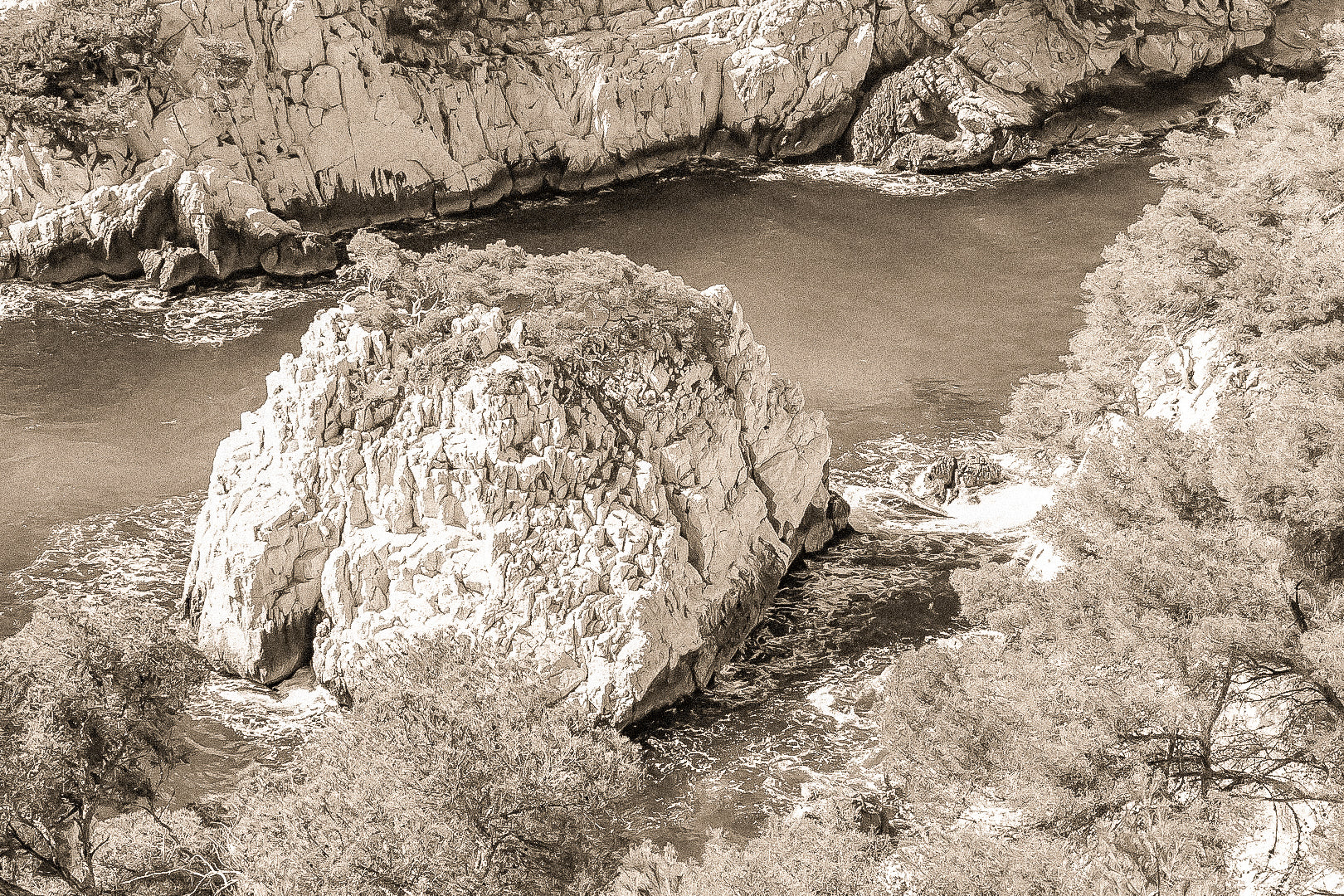 Petit îlot rocheux couvert de pins au centre d’une anse turquoise dans les calanques, vintage