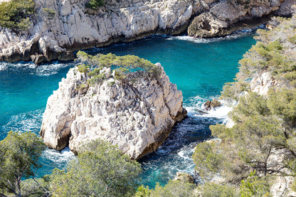 Petit îlot rocheux couvert de pins au centre d’une anse turquoise dans les calanques