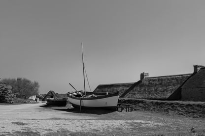 Barques tirées au sec devant les toits de chaume et murets de pierre à Meneham, ambiance ancienne, noir et blanc 