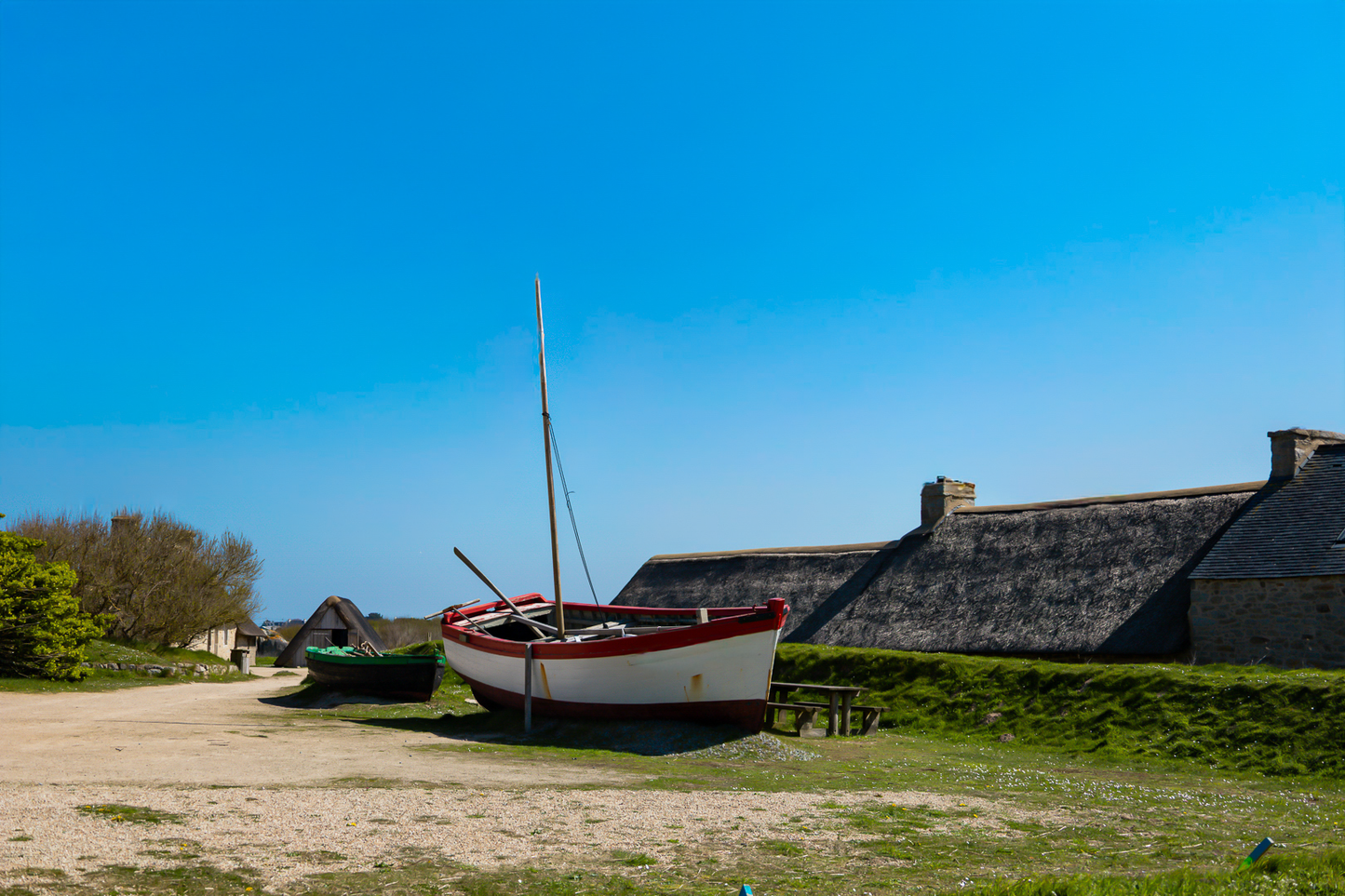 Barques tirées au sec devant les toits de chaume et murets de pierre à Meneham,  couleur