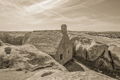 La maison emblématique de Meneham nichée entre deux énormes blocs de granit, vue d’ensemble en sépia vintage.