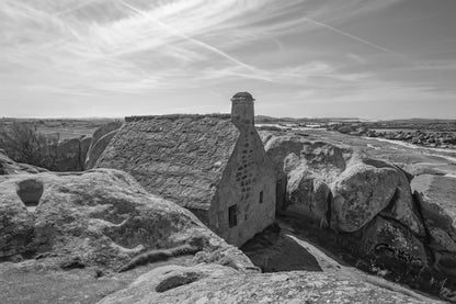 La maison emblématique de Meneham nichée entre deux énormes blocs de granit, vue d’ensemble, noir et blanc