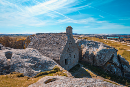 La maison emblématique de Meneham nichée entre deux énormes blocs de granit, vue d’ensemble, couleur