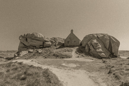 Façade de la maison des gardes encadrée par deux rochers monumentaux, Meneham (Kerlouan), traitement sepia