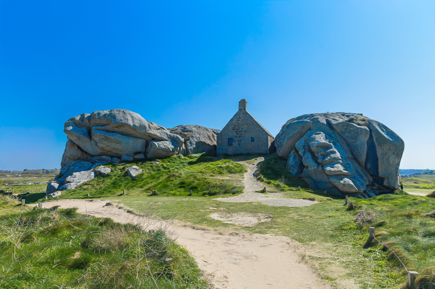 Façade de la maison des gardes encadrée par deux rochers monumentaux, Meneham (Kerlouan), couleur