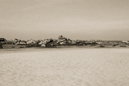 Grande plage claire avec rochers épars et ligne d’horizon marine, ambiance sépia vintage à Meneham