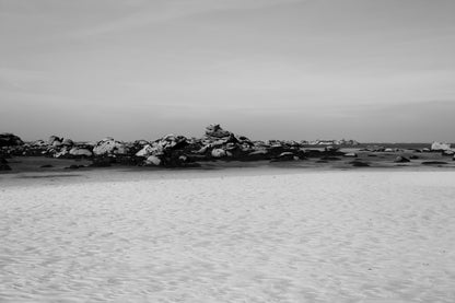 Grande plage claire avec rochers épars et ligne d’horizon marine, noir et blanc à Meneham