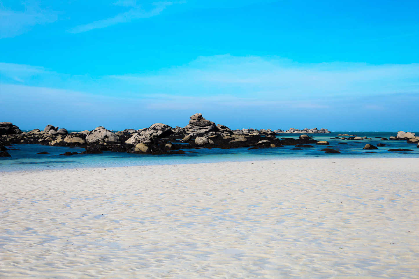Grande plage claire avec rochers épars et ligne d’horizon marine, couleur à Meneham