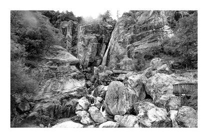 Panorama de la cascade du Ray entourée de falaises et de blocs rocheux, ambiance montagneuse, noir et blanc avec bordure