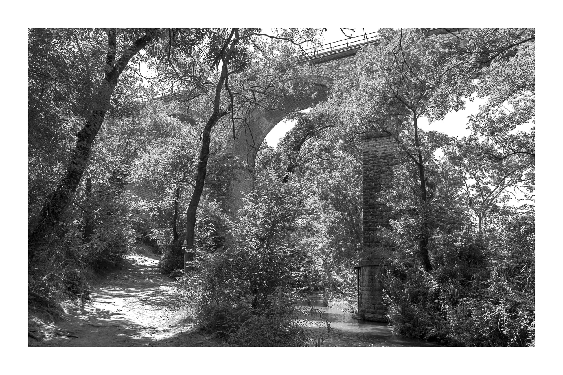 Viaduc de pierre traversant une vallée boisée au-dessus de la rivière de l’Arc, noir et blanc avec bordure