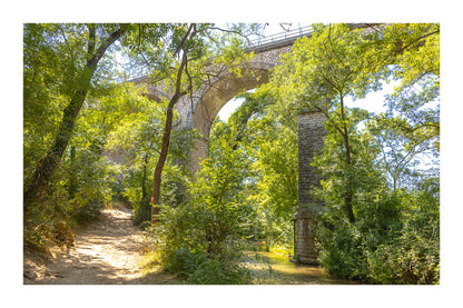 Viaduc de pierre traversant une vallée boisée au-dessus de la rivière de l’Arc avec bordure