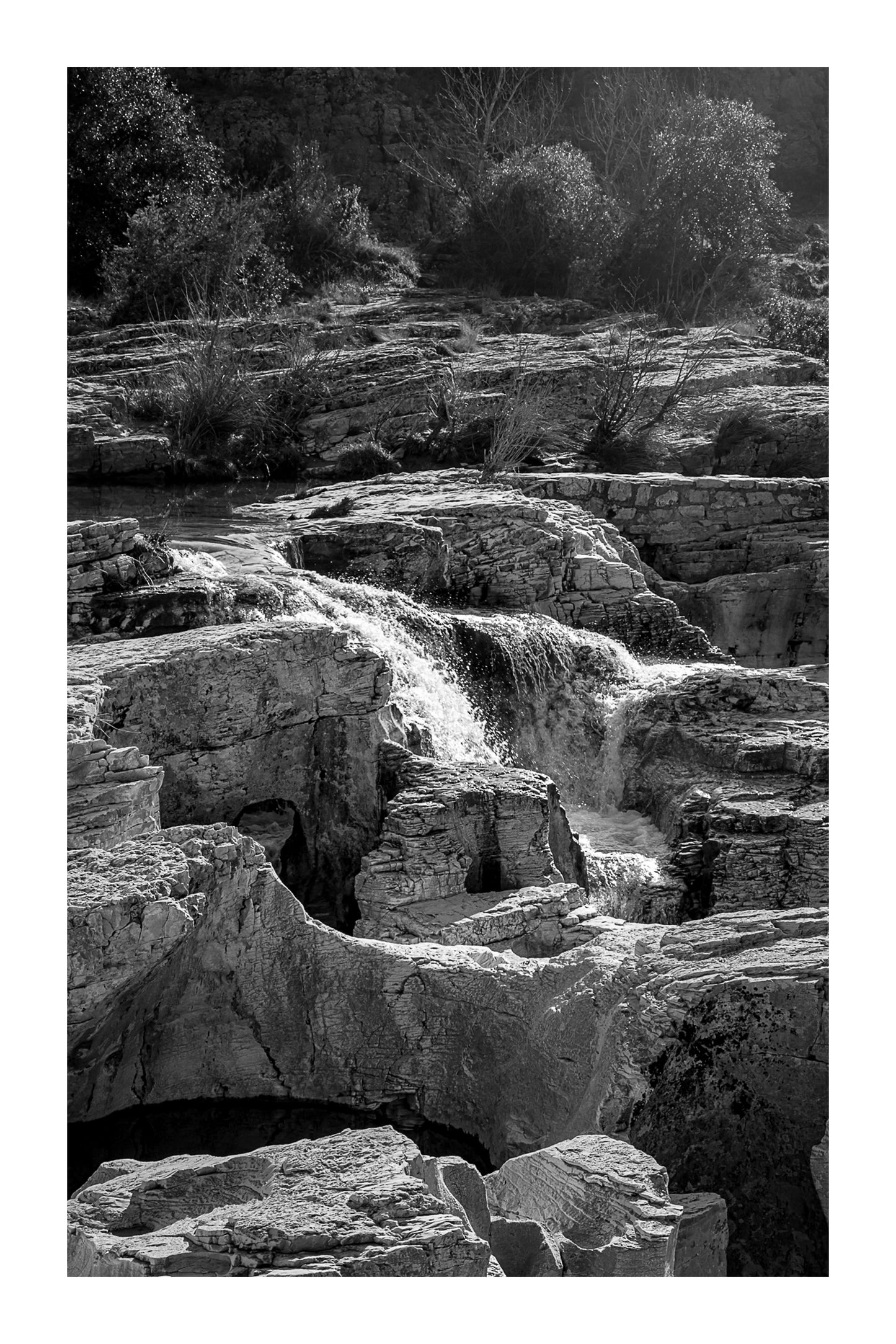 Bloc de calcaire creusé et cascade encaissée à la cascade du Sautadet, paysage minéral dominé par les rochers, noir et blanc avec bordure
