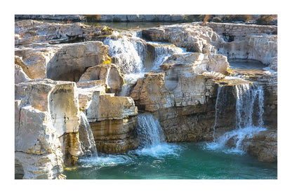 Ensemble de chutes superposées tombant dans un bassin turquoise à la cascade du Sautadet avec bordure