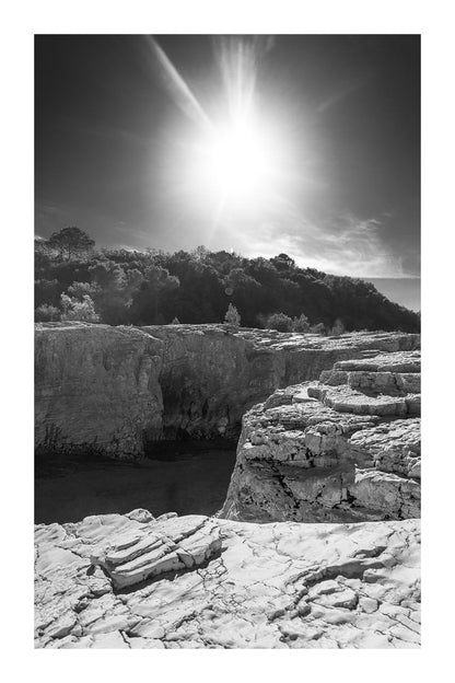 Soleil au zénith au-dessus des falaises claires et de l’eau bleu profond à la cascade du Sautadet, noir et blanc avec bordure