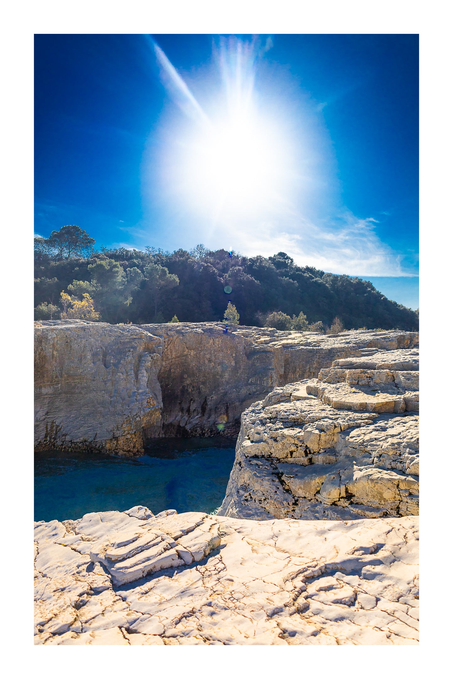 Soleil au zénith au-dessus des falaises claires et de l’eau bleu profond à la cascade du Sautadet avec bordure