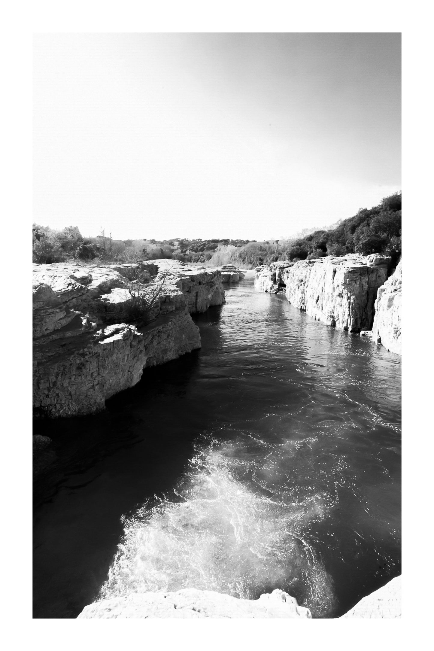 Bras de la Cèze encaissé entre deux parois calcaires, eau émeraude et remous en premier plan, noir et blanc avec bordure