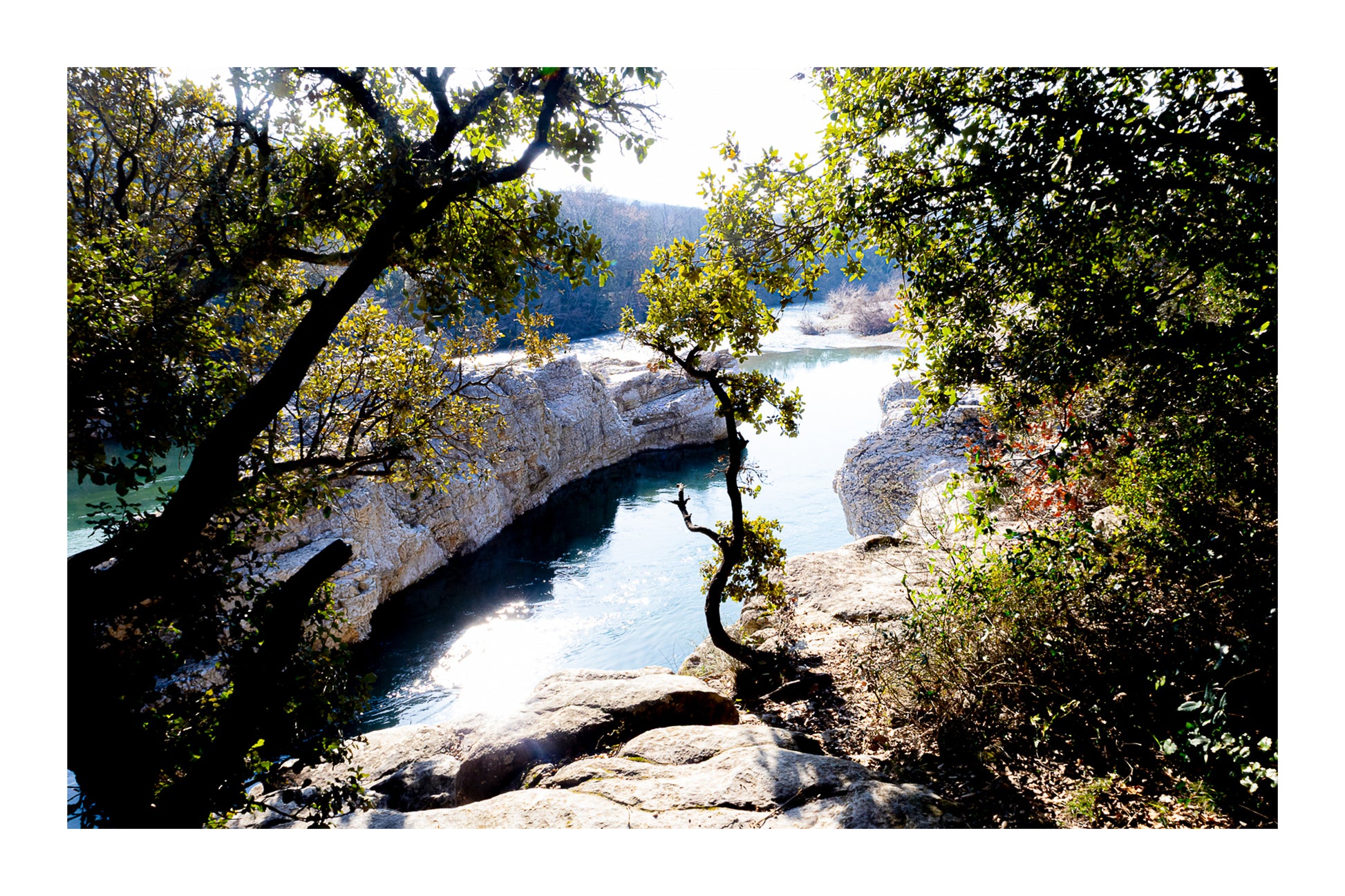 Courbe de la rivière Cèze vue à travers un encadrement d’arbres et de rochers à la cascade du Sautadet avec bordure
