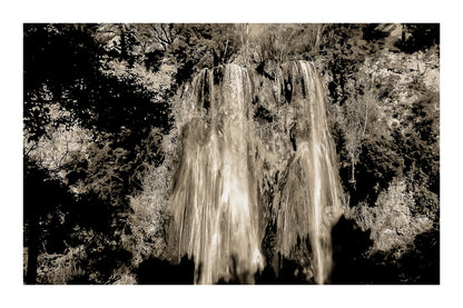 Grande cascade de Sillans tombant en rideaux blancs sur une paroi ocre et moussue, encadrée par la végétation, vintage avec bordure
