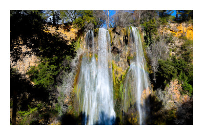 Grande cascade de Sillans tombant en rideaux blancs sur une paroi ocre et moussue, encadrée par la végétation avec bordure