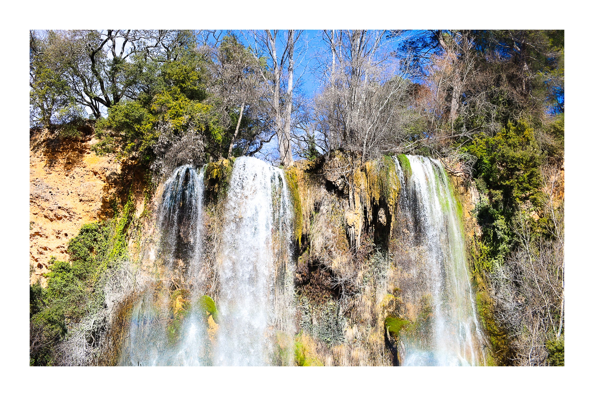 Deux pans de cascade à Sillans dévalant la falaise, entourés d’arbres nus et de mousse verte avec bordure